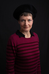 Paris, France - 12 08 2022: Studio shot of a woman wearing a black shirt, a black beret a, black and red striped sweater and jewelry