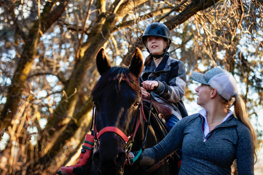 A young girl with Cerebral Palsy and her trainer working with a horse on a trail ride during a Hippotherapy session; Westlock, Alberta, Canada