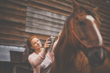 Pretty, young, redhead woman with her lovely horse, during her favorite leisure