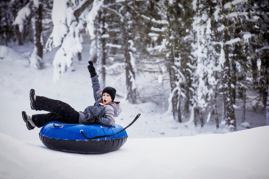 Young boy tubing down a ski hill; Fairmont Hot Springs, British Columbia, Canada