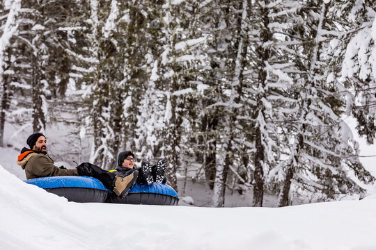 Father and son tubing down a ski hill; Fairmont Hot Springs, British Columbia, Canada