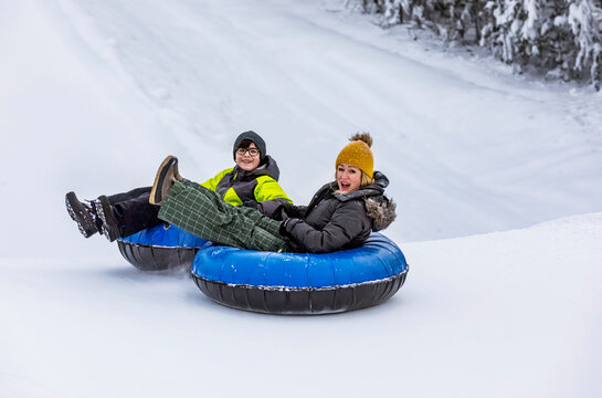 Mother and son tubing down a ski hill; Fairmont Hot Springs, British Columbia, Canada