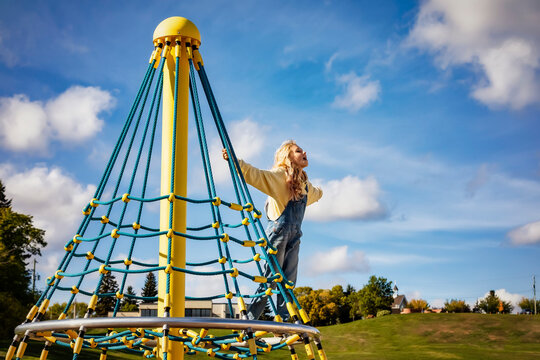 Young girl playing on a merry-go-round in a school playground on a warm fall afternoon; St. Albert, Alberta, Canada
