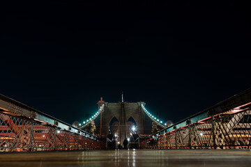 Fototapeta na wymiar Brooklyn Bridge in New York at night. Skyscrapers of a large metropolis. Night city at long exposure. Towers in the big city.