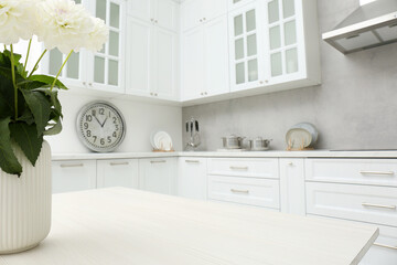 Fototapeta na wymiar Bouquet of flowers on stylish white wooden table in kitchen, space for text. Interior design
