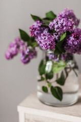 A bouquet of fresh lilacs in a glass vase top view.