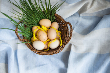 Beautiful painted Easter eggs, one egg with a cute face, eggs lie in a wooden basket along with...