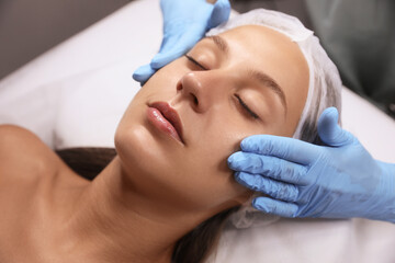 Fototapeta na wymiar Young woman receiving facial massage in salon