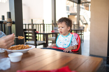 One and half year old baby boy having a meal in the restaurant with his mother