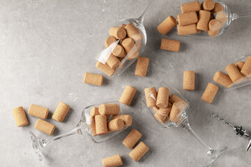 Glasses with wine corks and corkscrew on light table, flat lay