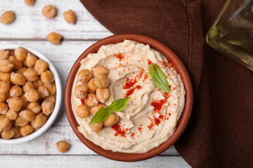 Delicious hummus with chickpeas and paprika served on white wooden table, flat lay