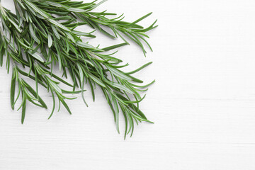 Fresh green rosemary twigs on white wooden table, top view. Space for text