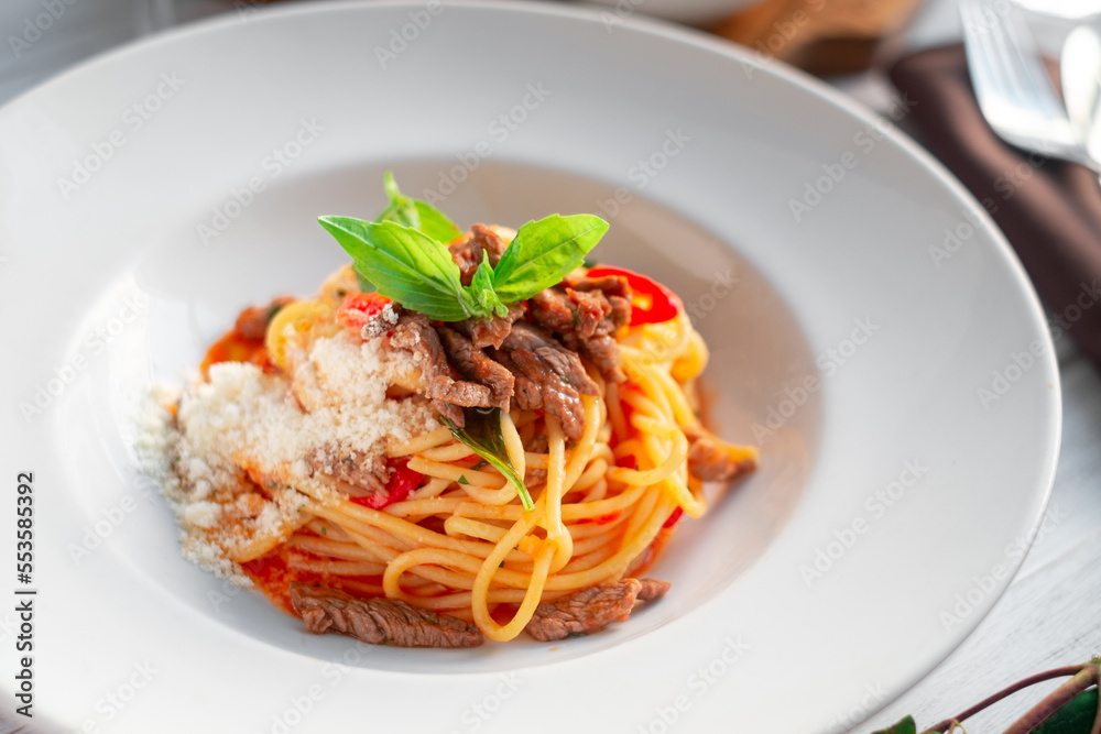 Wall mural Spaghetti pasta with tomato sauce and beef stew, tomatoes, parmesan cheese and fresh basil on a wooden background. Italian cuisine