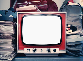 An old CRT TV set inside a bright storage room, with VHS tapes and paper. Blank white screen.
