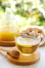 Cup of delicious tea with lemon and honey on white wooden table outdoors