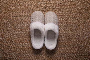 Fototapeta na wymiar Pair of beautiful soft slippers on wicker carpet, top view