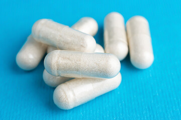 White pills, medicine capsules, vitamins or drugs on blue background, medication treatment, health care concept