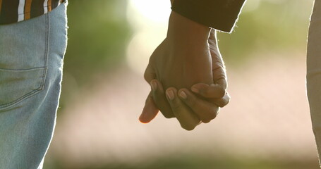 Close-up of hands joining together with sunlight flare in the background. Beautiful romantic moment...