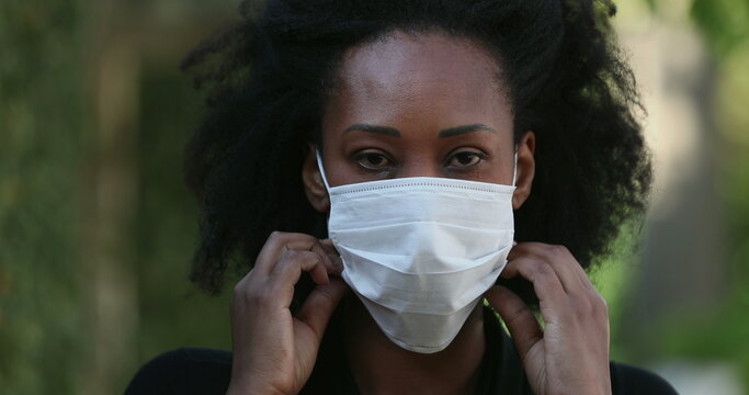 Black Woman Putting Covid-19 Face Mask Outside Looking At Camera