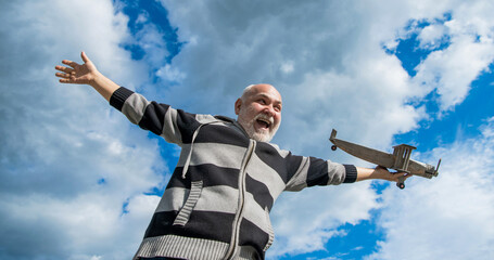 surprised senior man on sky background. senior man at retirement. senior retired man with toy plane