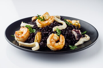 delicious black rice with shrimps and seafood on a white background