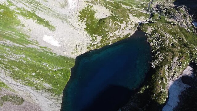 Quadrocopter shoot to blue lake between high mountains in the wild nature. The beautiful view from sky with drone