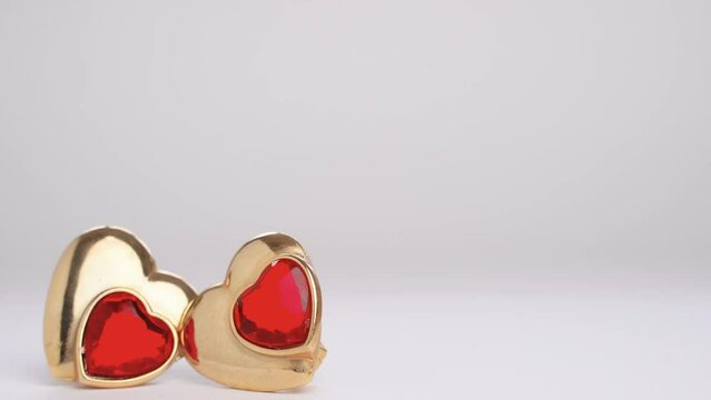 Hand throws heart shaped earring with ruby. Polyamory. Threesome. Infidelity