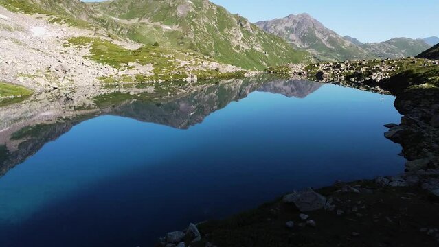 Quadrocopter shoot to blue lake between high mountains in the wild nature. The beautiful view from sky with drone