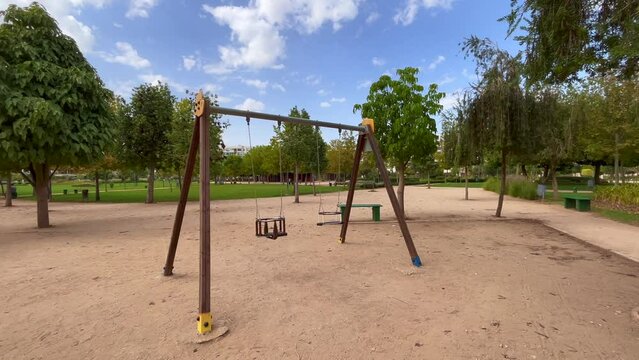 An empty swing in the park with trees in the background