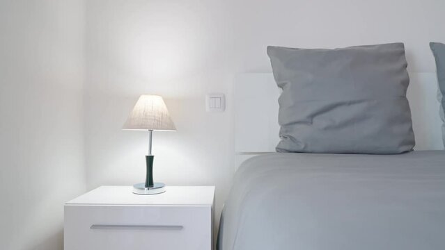 Modern minimalist bedroom for relaxation and sleep with candy on towels. Minimalistic lamp on bedside tables for things gray pillows.