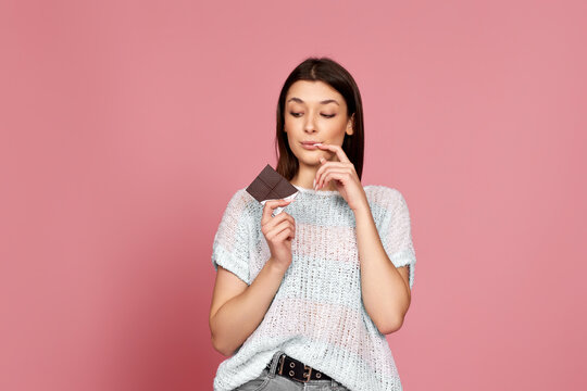 young woman in sweater holding chocolate bar