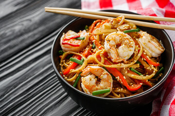 fried wok shrimp noodles on a black wooden rustic background