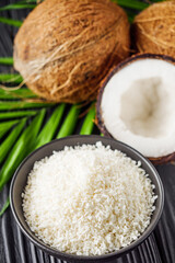 fresh natural coconut and shavings dried flakes on black wooden background