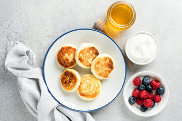 Cheese fritters, Syrniki served with berries, sour cream and honey. Sweet breakfast cheese pancakes...