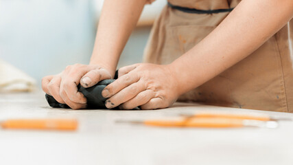The master of sculpting pottery working in a studio. Kneading a piece of clay with her hands. Tools on the table