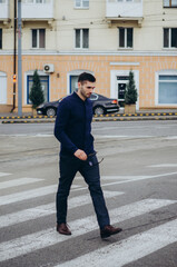 a man with glasses in his hand crosses the road