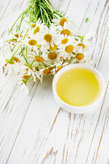 aromatic chamomile essential oil on a white wooden rustic background