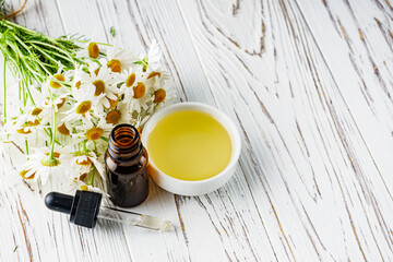aromatic chamomile essential oil on a white wooden rustic background