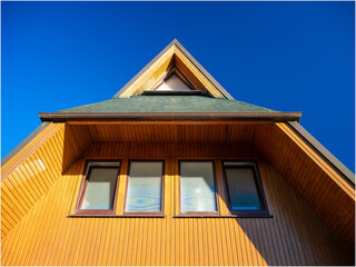 Modern exterior of private house. Bottom view of attic. Blue sky. Sunny day.