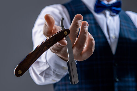 photo with selective focus of barber blade in hand of man. barber man hold blade.