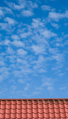 Red tiled roof. CLouds in blue sky. Close-up.