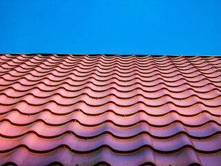 Red clay ceramic tiled roof. Blue sky. Close-up.
