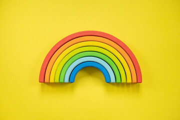 Wooden multicolored rainbow Montessori material for kids early development isolated on yellow