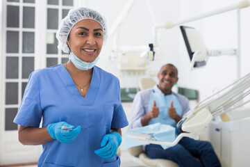 Portrait of successful professional woman dentist standing in blue uniform in modern medical dental office