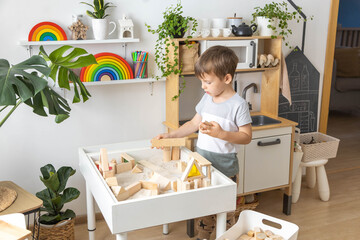 Cute boy kid playing sensory box kinetic sand table with Montessori wooden materials