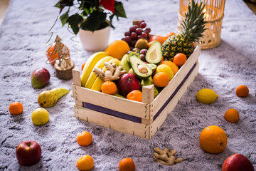 Winter healthy fruit wooden box with apples, kiwi, banana, avocado, ginger, pineapple, lemons, oranges and more ready for Christmass table.
