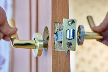 Locksmith is repairing faulty lever door handle with latch. - obrazy, fototapety, plakaty
