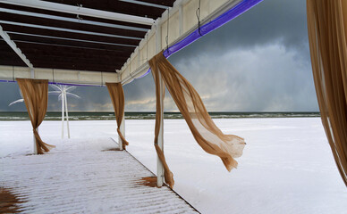 Terrace of a summer cafe on the beach in winter. Baltic Sea beach in snowy winter.