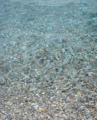 Background with a transparent sea surface with sea pebbles at the bottom