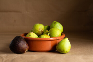 Fresh figs in a clay plate on a light brown background